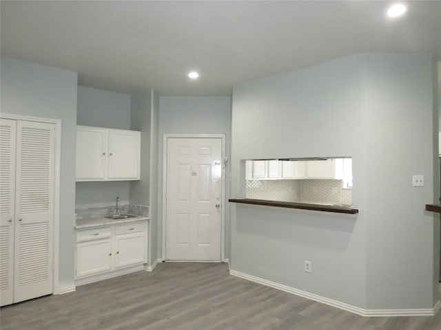 kitchen featuring white cabinets, light wood-type flooring, sink, and tasteful backsplash