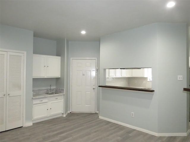 4715 N Galloway Ave Unit 104, Mesquite, TX 75150 - kitchen with white cabinets, wood finished floors, a sink, recessed lighting, and baseboards