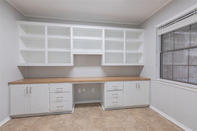 unfurnished office featuring built in desk, a textured ceiling, and ornamental molding