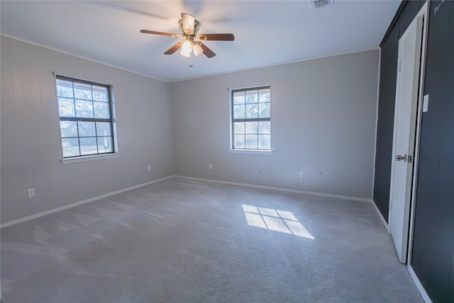 spare room with carpet, a wealth of natural light, and ceiling fan