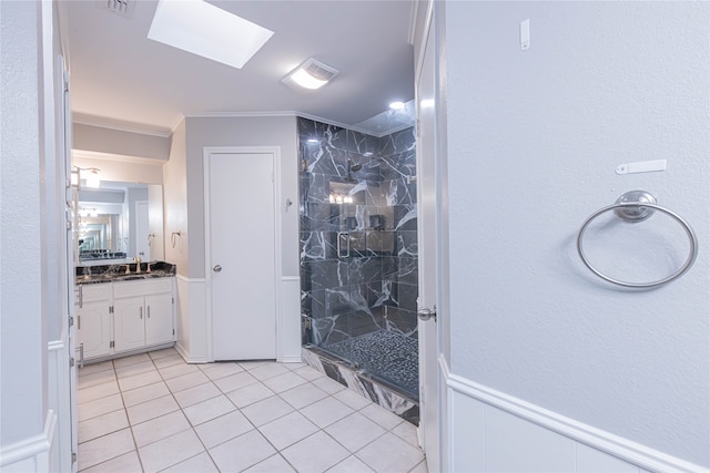 bathroom with a skylight, tile patterned flooring, crown molding, tiled shower, and vanity