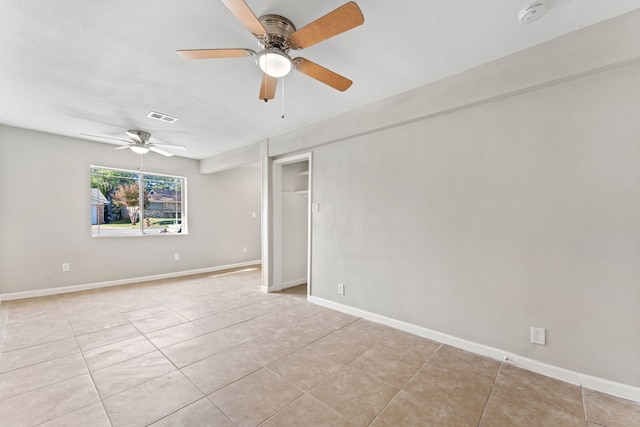 spare room with light tile patterned floors, a ceiling fan, visible vents, and baseboards