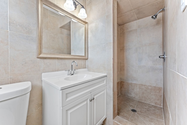 bathroom with toilet, vanity, and tiled shower