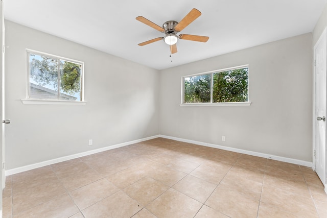 empty room featuring ceiling fan, a wealth of natural light, and light tile patterned floors