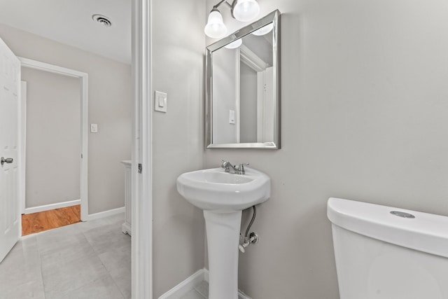 bathroom with toilet, a sink, visible vents, and baseboards