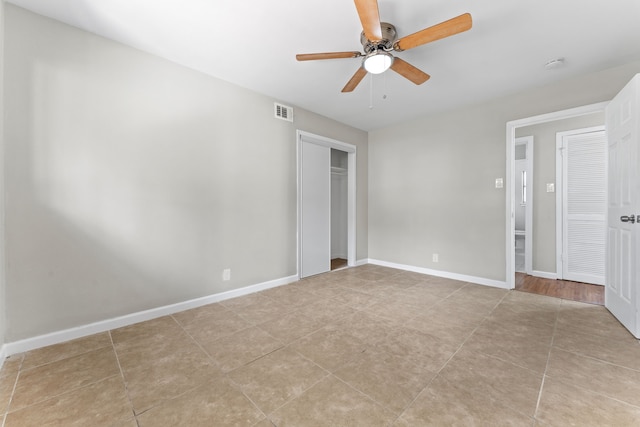 unfurnished bedroom with light tile patterned floors, baseboards, visible vents, ceiling fan, and a closet