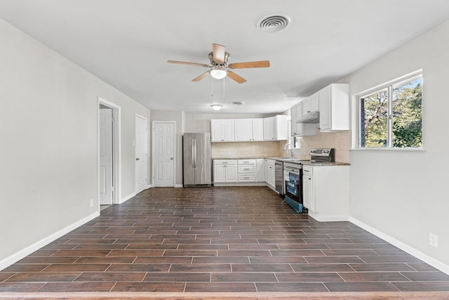 kitchen featuring light stone countertops, decorative backsplash, white cabinetry, and appliances with stainless steel finishes