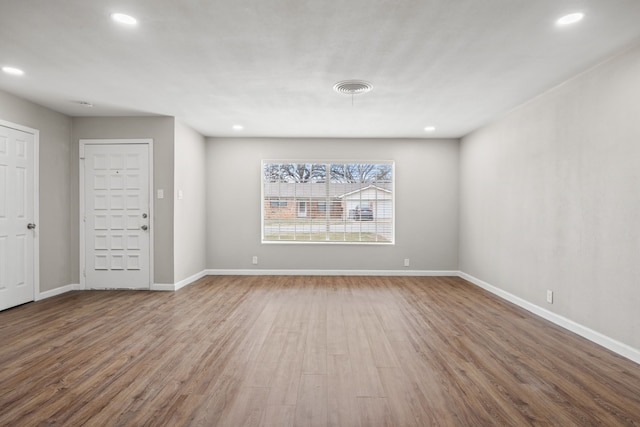 empty room featuring visible vents, baseboards, wood finished floors, and recessed lighting