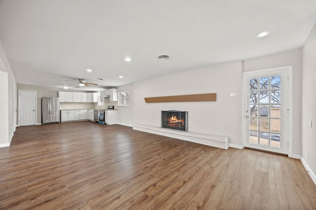 unfurnished living room with light wood-style floors, a healthy amount of sunlight, and visible vents