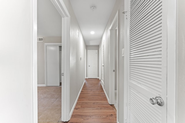 corridor with light wood-type flooring, baseboards, and visible vents