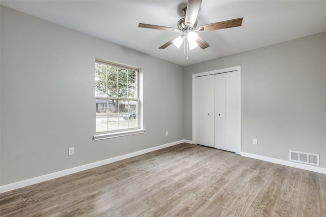 unfurnished bedroom with ceiling fan, a closet, and light wood-type flooring