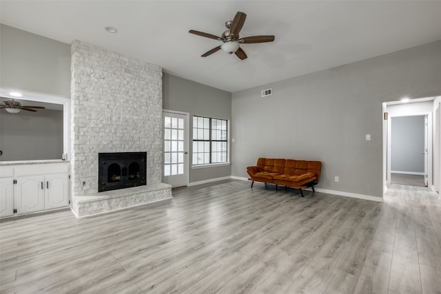 living room featuring ceiling fan, light wood-type flooring, and a fireplace