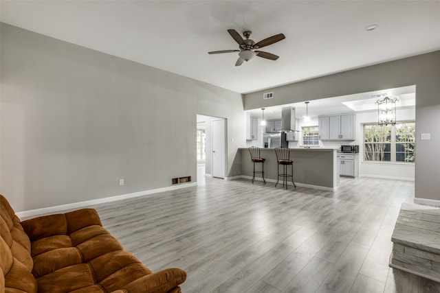 living room featuring ceiling fan with notable chandelier and light hardwood / wood-style floors