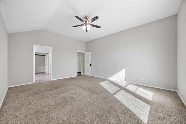 unfurnished bedroom with light carpet, a walk in closet, vaulted ceiling, and ceiling fan