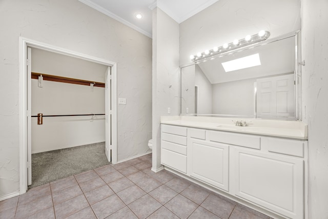 bathroom featuring vanity, crown molding, a skylight, tile patterned flooring, and toilet