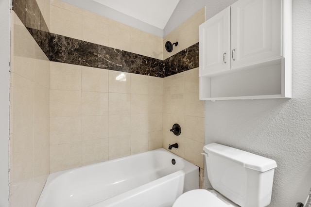 bathroom featuring tiled shower / bath combo, toilet, and lofted ceiling