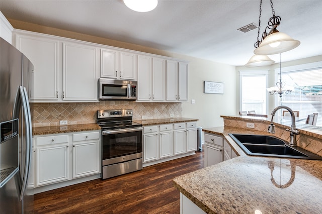 kitchen with pendant lighting, white cabinets, sink, stainless steel appliances, and a chandelier