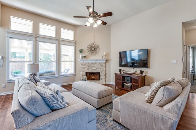 living room featuring a stone fireplace, ceiling fan, and dark hardwood / wood-style floors