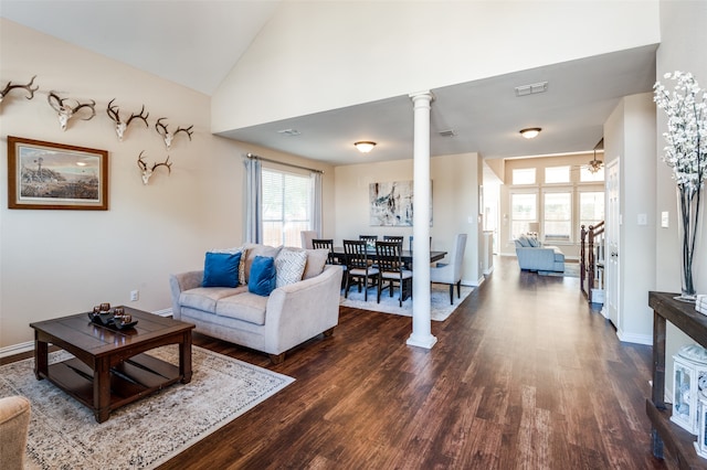 living room with decorative columns, ceiling fan, high vaulted ceiling, and dark wood-type flooring