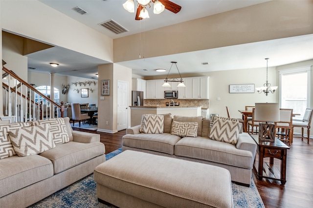 living room featuring dark hardwood / wood-style flooring and ceiling fan with notable chandelier