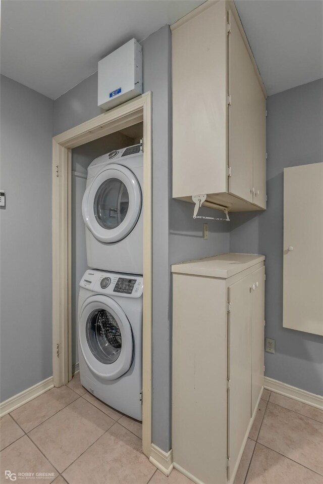 clothes washing area featuring stacked washer / drying machine and light tile patterned floors