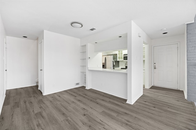 unfurnished living room featuring sink and dark hardwood / wood-style floors