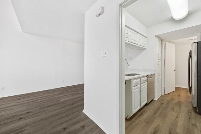 kitchen featuring appliances with stainless steel finishes, dark hardwood / wood-style flooring, a textured ceiling, sink, and white cabinets