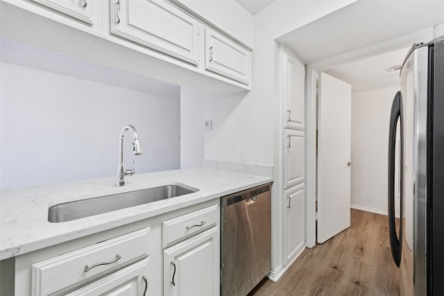 kitchen featuring appliances with stainless steel finishes, light wood-type flooring, white cabinetry, and sink