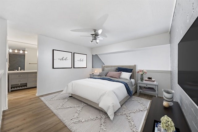 bedroom featuring light hardwood / wood-style floors, ensuite bath, and ceiling fan