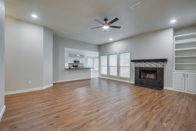 unfurnished living room featuring ceiling fan, light wood-type flooring, and a fireplace