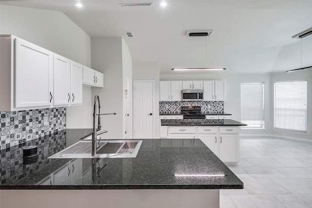 kitchen with pendant lighting, white cabinets, black range, sink, and decorative backsplash