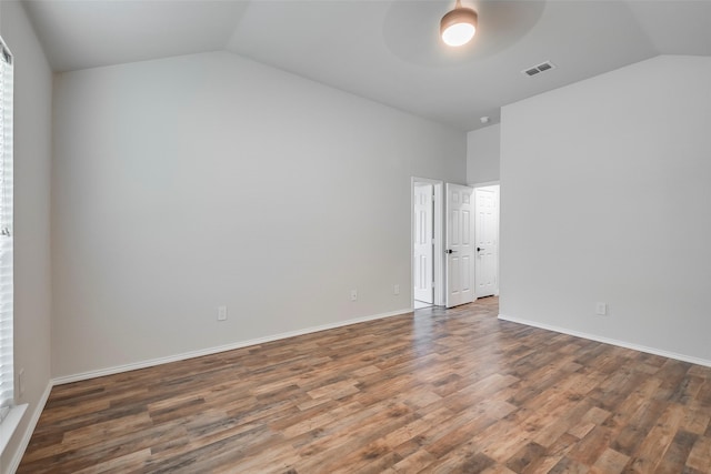 unfurnished room featuring dark wood-type flooring and lofted ceiling