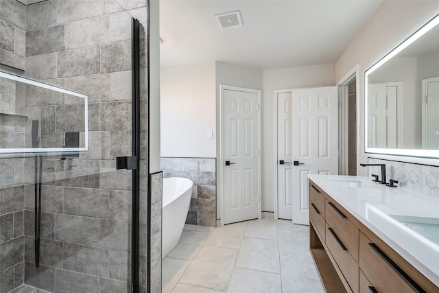 bathroom with tile patterned flooring, vanity, tile walls, and plus walk in shower