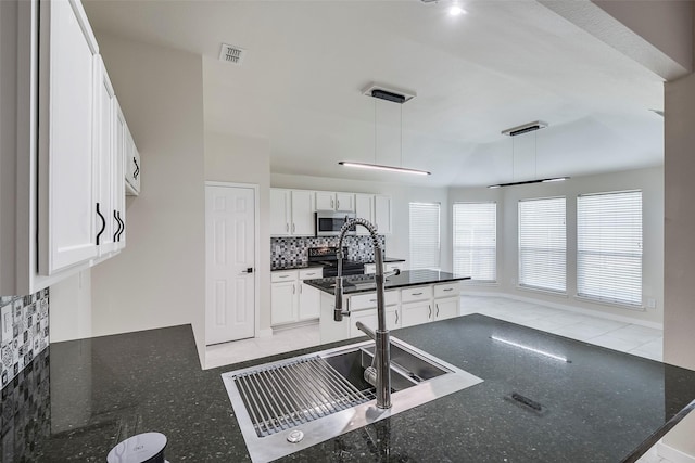 kitchen featuring pendant lighting, dark stone counters, white cabinets, sink, and decorative backsplash