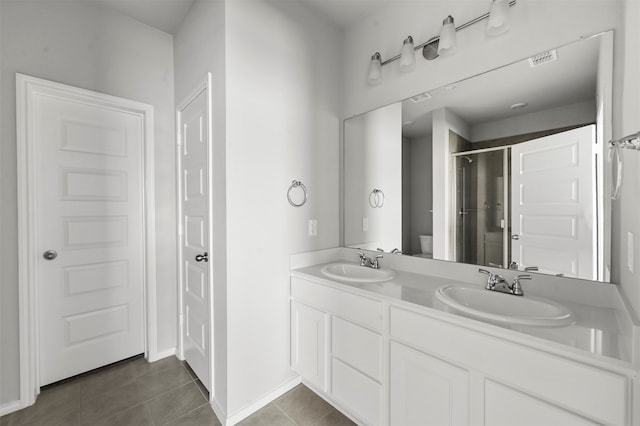 bathroom featuring tile patterned floors, vanity, toilet, and a shower with shower door