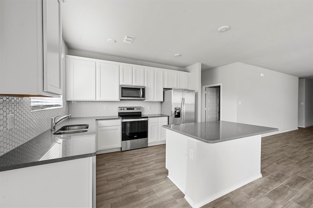 kitchen with appliances with stainless steel finishes, light hardwood / wood-style flooring, white cabinetry, and sink