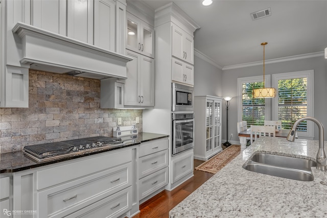 kitchen with stainless steel appliances, visible vents, ornamental molding, a sink, and premium range hood