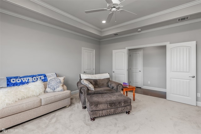 carpeted living room featuring a ceiling fan, baseboards, visible vents, a tray ceiling, and crown molding