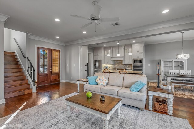 living room featuring baseboards, visible vents, ornamental molding, dark wood-type flooring, and stairs