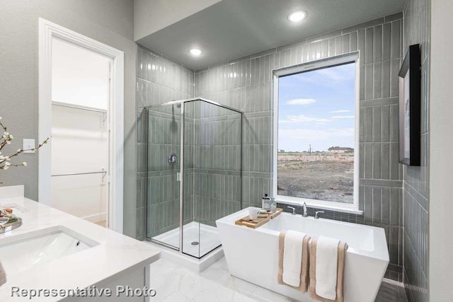 bathroom featuring separate shower and tub, vanity, and tile walls