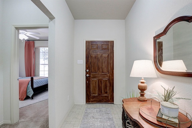 foyer featuring ceiling fan and light carpet