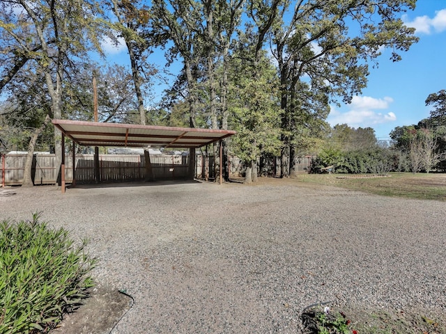 view of car parking featuring driveway, fence, and a detached carport