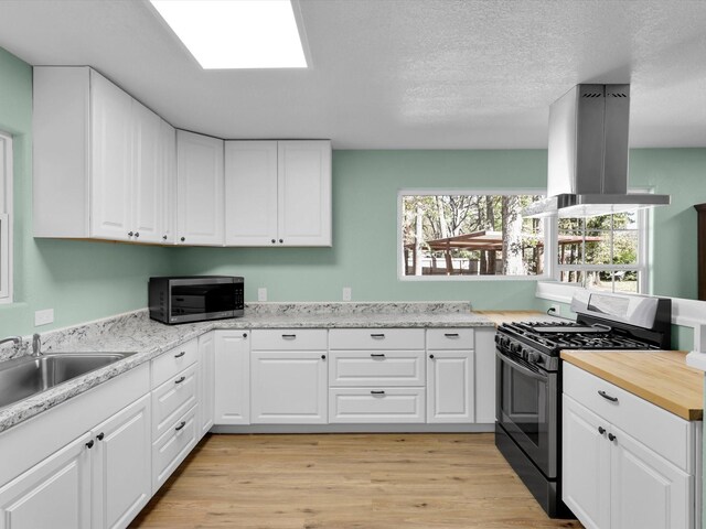 kitchen featuring a sink, light wood-style floors, range with gas cooktop, stainless steel microwave, and island exhaust hood