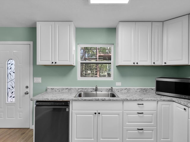 kitchen with dishwashing machine, stainless steel microwave, a sink, and white cabinetry