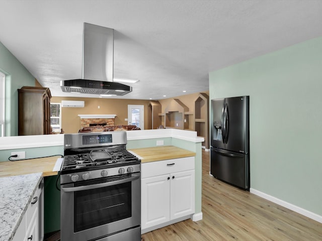 kitchen with stainless steel gas range, butcher block countertops, black refrigerator with ice dispenser, and extractor fan