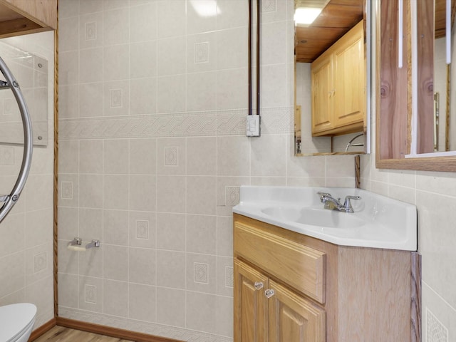 half bath with tile walls, toilet, and vanity