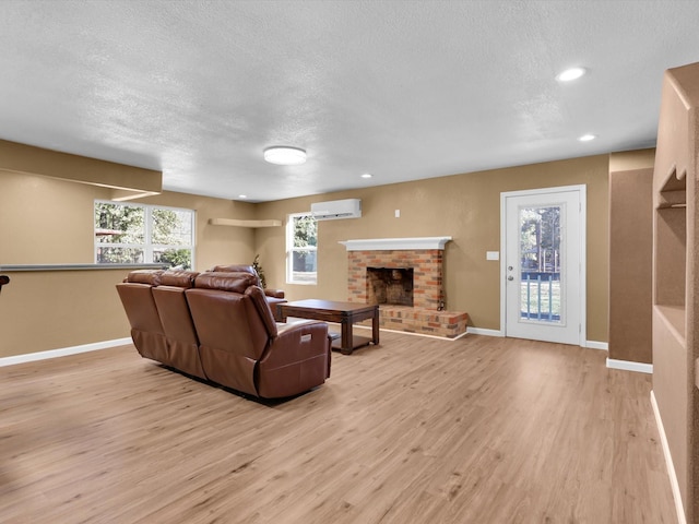 living area with light wood-style floors, a fireplace, baseboards, and a wall mounted AC