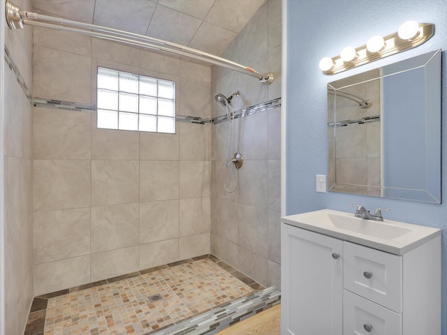 bathroom with tiled shower and vanity