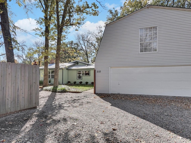 view of side of property with a garage, driveway, and fence