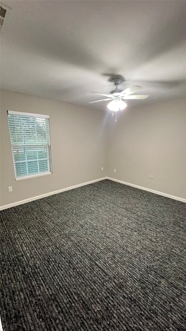 empty room with dark colored carpet and ceiling fan